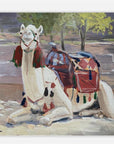 Painting of a decorated camel with a saddle on a stone surface.