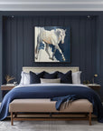 Modern bedroom with dark blue paneled walls, a bed with blue and white bedding, and a horse painting above the bed.